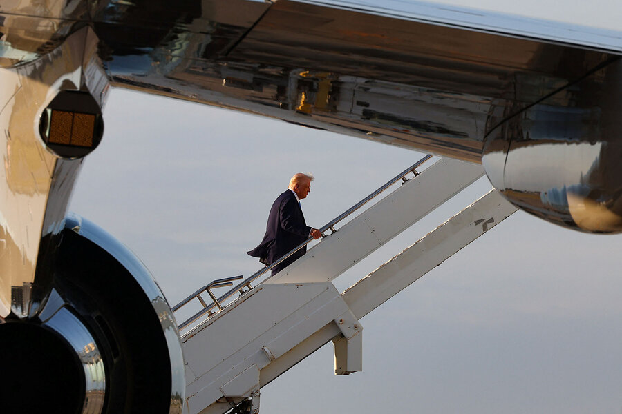 Donald Trump, in a dark suit, climbs stairs to board Air Force One.