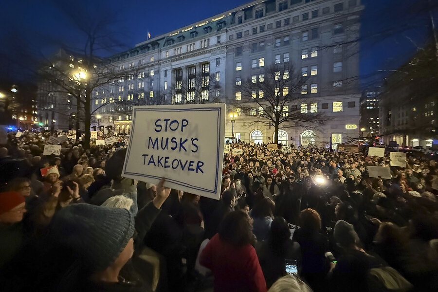 People hold signs while protesting against Elon Musk outside the U.S. Treasury Department in Washington. 