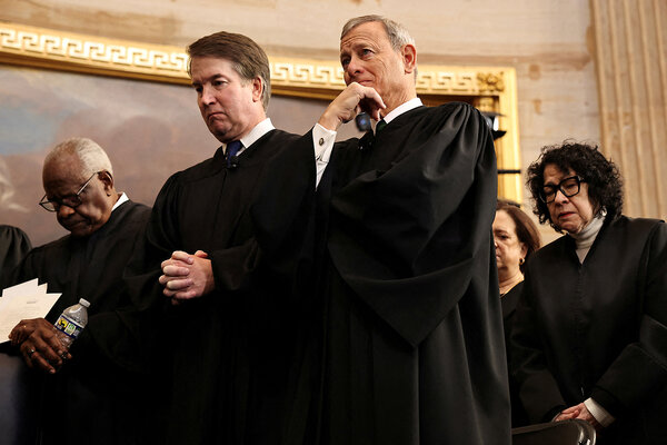 Wearing black robes, members of the U.S. Supreme Court stand in the Capitol Rotunda.