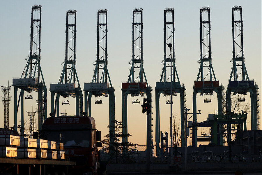 Six tall gantry cranes, used to load cargo off ships, are silhouetted against the sky in Tianjin, China.