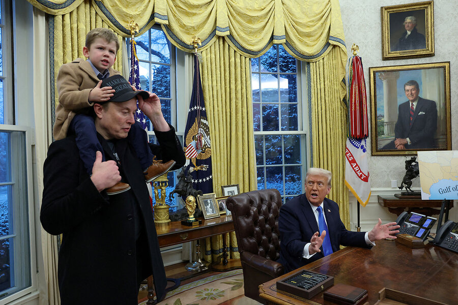 Elon Musk carries his son on his shoulders in the Oval Office while he stands next to a seated President Donald Trump.