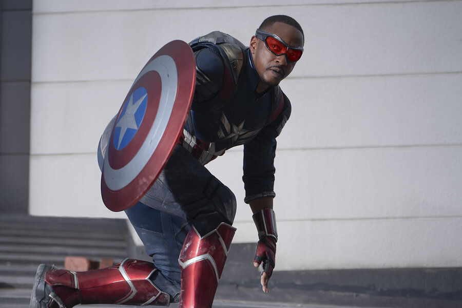 Anthony Mackie, who stars as Captain America, crouches and holds a red, white, and blue shield.