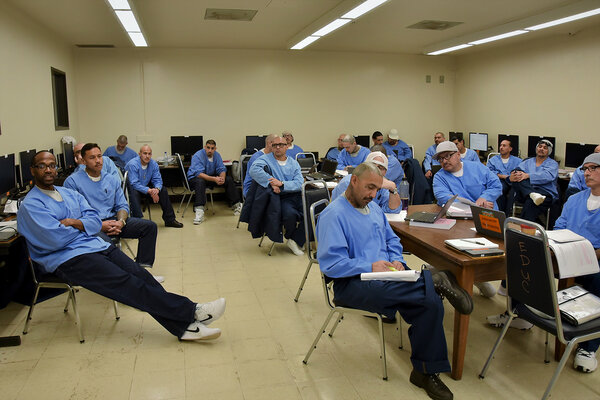 Members of a class at Pelican Bay State Prison sit in chairs in a classroom and have a discussion.