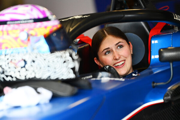 Driver Lia Block sits in a race car looking out and smiling ahead of an F1 Academy race in the Netherlands