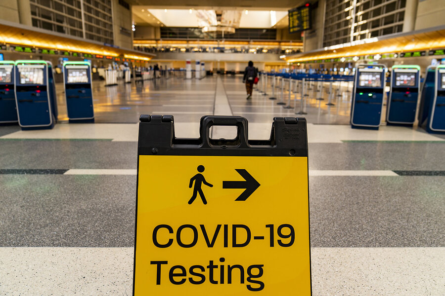 A sign in a nearly empty airport terminal points people toward COVID-19 testing.