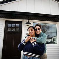 Iliana Damascena hugs her new wife, Yara, in front of the door to their new home in Cranston, Rhode Island.