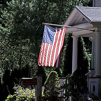 An American flag is backlit by the sun as it hangs outside a house in Hingham, Massachusetts.