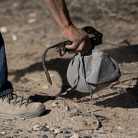 Robert Ardovino picks up a hat, belt, and shoelaces, all presumed to be left there by migrants who crossed the U.S.-Mexico border, on his property May 1, 2025, in Sunland Park, New Mexico. 
