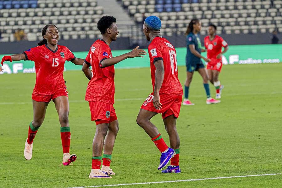 A group of people in red uniforms standing on a grass sports field.