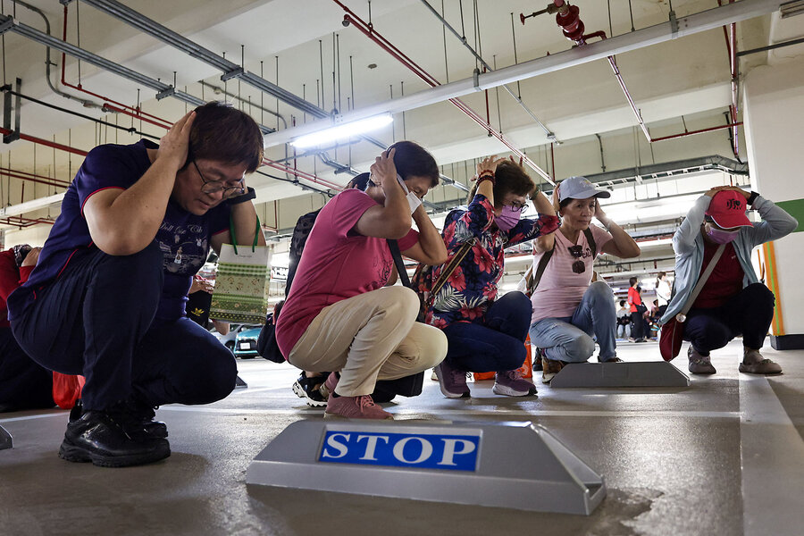 A group of people gathered indoors, kneeling on the floor near several stop signs.